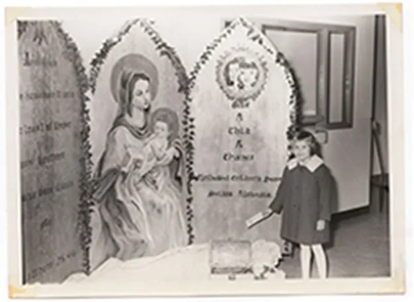 Young girl standing beside a religious display at the children’s home in 1939