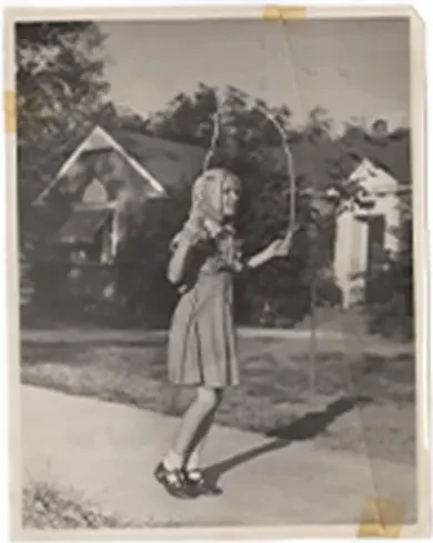 Young girl jumping rope outside a residential home in 1968