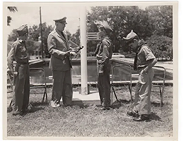 Three uniformed youths and a uniformed adult participating in an outdoor flag ceremony in 1971