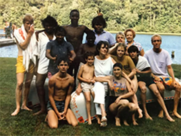 Children and adults gathered beside a lake during a group outing in 1980